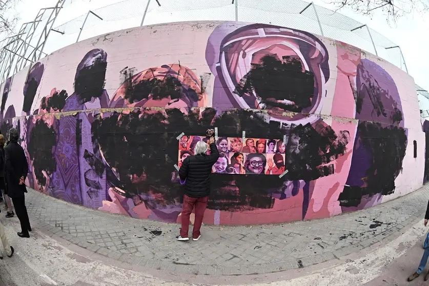 GRAF596. MADRID, 08/03/2021.- Una mujer junto al mural feminista "La uni&oacute;n hace la fuerza" del barrio de Ciudad Lineal (Madrid) que este lunes, D&iacute;a de la Mujer, ha amanecido vandalizado con pintura negra que cubre los rostros de las mujeres homenajeadas en sus paredes. EFE/ Fernando Villar