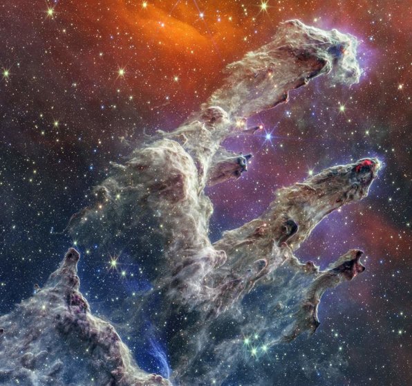 By combining images of the iconic Pillars of Creation from two cameras aboard the NASA/ESA/CSA James Webb Space Telescope, the Universe has been framed in its infrared glory. Webb???s near-infrared image was fused with its mid-infrared image, setting this star-forming region ablaze with new details. Myriad stars are spread throughout the scene. The stars primarily show up in near-infrared light, marking a contribution of Webb???s Near-Infrared Camera (NIRCam). Near-infrared light also reveals thousands of newly formed stars ??? look for bright orange spheres that lie just outside the dusty pillars. In mid-infrared light, the dust is on full display. The contributions from Webb???s Mid-Infrared Instrument (MIRI) are most apparent in the layers of diffuse, orange dust that drape the top of the image, relaxing into a V. The densest regions of dust are cast in deep indigo hues, obscuring our view of the activities inside the dense pillars. Dust also makes up the spire-like pillars that extend from the bottom left to the top right. This is one of the reasons why the region is overflowing with stars ??? dust is a major ingredient of star formation. When knots of gas and dust with sufficient mass form in the pillars, they begin to collapse under their own gravitational attraction, slowly heat up, and eventually form new stars. Newly formed stars are especially apparent at the edges of the top two pillars ??? they are practically bursting onto the scene. At the top edge of the second pillar, undulating detail in red hints at even more embedded stars. These are even younger, and are quite active as they form. The lava-like regions capture their periodic ejections. As stars form, they periodically send out supersonic jets that can interact within clouds of material, like these thick pillars of gas and dust. These young stars are estimated to be only a few hundred thousand years old, and will continue to form for millions of years. Almost everything you see in this scene is local. The distant universe is largely blocked from our view both by the interstellar medium, which is made up of sparse gas and dust located between the stars, and a thick dust lane in our Milky Way galaxy. As a result, the stars take center stage in Webb???s view of the Pillars of Creation. The Pillars of Creation is a small region within the vast Eagle Nebula, which lies 6,500 light-years away. Revisit Webb???s near-infrared image and its its mid-infrared image. The Pillars of Creation was made famous by the NASA/ESA Hubble Space Telescope in 1995, and again in 2014. MIRI was contributed by ESA and NASA, with the instrument designed and built by a consortium of nationally funded European Institutes (The MIRI European Consortium) in partnership with JPL and the University of Arizona. Webb???s NIRCam was built by a team at the University of Arizona and Lockheed Martin???s Advanced Technology Center. [Image Description: Semi-opaque layers of blue, purple, and grey gas and dust start at the bottom left and rise toward the top right. There are three prominent pillars. The left pillar is the largest and widest. The background is orange near the top and dark blue and purple near the bottom. Some blue and white stars dot the overall scene.]