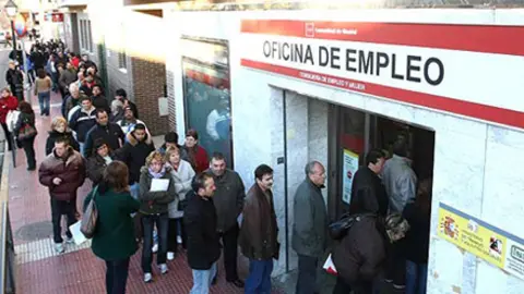 Un grupo de personas hacen cola a las puertas de la Oficina de Empleo