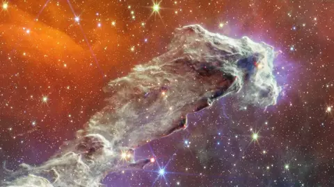 By combining images of the iconic Pillars of Creation from two cameras aboard the NASA/ESA/CSA James Webb Space Telescope, the Universe has been framed in its infrared glory. Webb???s near-infrared image was fused with its mid-infrared image, setting this star-forming region ablaze with new details. Myriad stars are spread throughout the scene. The stars primarily show up in near-infrared light, marking a contribution of Webb???s Near-Infrared Camera (NIRCam). Near-infrared light also reveals thousands of newly formed stars ??? look for bright orange spheres that lie just outside the dusty pillars. In mid-infrared light, the dust is on full display. The contributions from Webb???s Mid-Infrared Instrument (MIRI) are most apparent in the layers of diffuse, orange dust that drape the top of the image, relaxing into a V. The densest regions of dust are cast in deep indigo hues, obscuring our view of the activities inside the dense pillars. Dust also makes up the spire-like pillars that extend from the bottom left to the top right. This is one of the reasons why the region is overflowing with stars ??? dust is a major ingredient of star formation. When knots of gas and dust with sufficient mass form in the pillars, they begin to collapse under their own gravitational attraction, slowly heat up, and eventually form new stars. Newly formed stars are especially apparent at the edges of the top two pillars ??? they are practically bursting onto the scene. At the top edge of the second pillar, undulating detail in red hints at even more embedded stars. These are even younger, and are quite active as they form. The lava-like regions capture their periodic ejections. As stars form, they periodically send out supersonic jets that can interact within clouds of material, like these thick pillars of gas and dust. These young stars are estimated to be only a few hundred thousand years old, and will continue to form for millions of years. Almost everything you see in this scene is local. The distant universe is largely blocked from our view both by the interstellar medium, which is made up of sparse gas and dust located between the stars, and a thick dust lane in our Milky Way galaxy. As a result, the stars take center stage in Webb???s view of the Pillars of Creation. The Pillars of Creation is a small region within the vast Eagle Nebula, which lies 6,500 light-years away. Revisit Webb???s near-infrared image and its its mid-infrared image. The Pillars of Creation was made famous by the NASA/ESA Hubble Space Telescope in 1995, and again in 2014. MIRI was contributed by ESA and NASA, with the instrument designed and built by a consortium of nationally funded European Institutes (The MIRI European Consortium) in partnership with JPL and the University of Arizona. Webb???s NIRCam was built by a team at the University of Arizona and Lockheed Martin???s Advanced Technology Center. [Image Description: Semi-opaque layers of blue, purple, and grey gas and dust start at the bottom left and rise toward the top right. There are three prominent pillars. The left pillar is the largest and widest. The background is orange near the top and dark blue and purple near the bottom. Some blue and white stars dot the overall scene.]