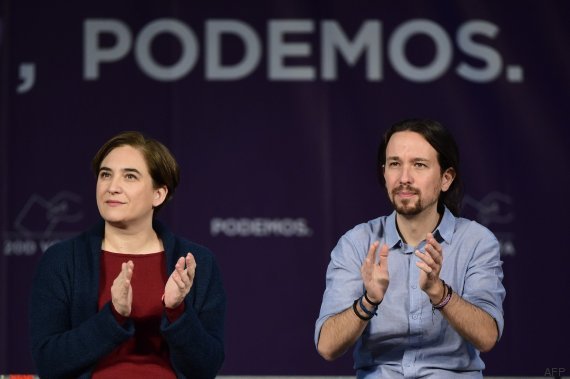 Leader of left wing party Podemos and candidate for the upcoming December 20 general election, Pablo Iglesias (R) and Barcelona Mayor Ada Colau applaud during a campaign meeting in Madrid on December 13, 2015. Public discontent over corruption across the political spectrum, as well as companies, unions, banks, celebrities, and even royalty could cost Spain's traditional parties dearly in upcoming elections as sky-high unemployment and austerity has seen the emergence of two new parties -- the anti-austerity Podemos and centrist Ciudadanos -- both threatening to the two-party monopoly at the polls says sociologist Jose Pablo Ferrandiz of polling institute Metroscopia. AFP PHOTO / JAVIER SORIANO